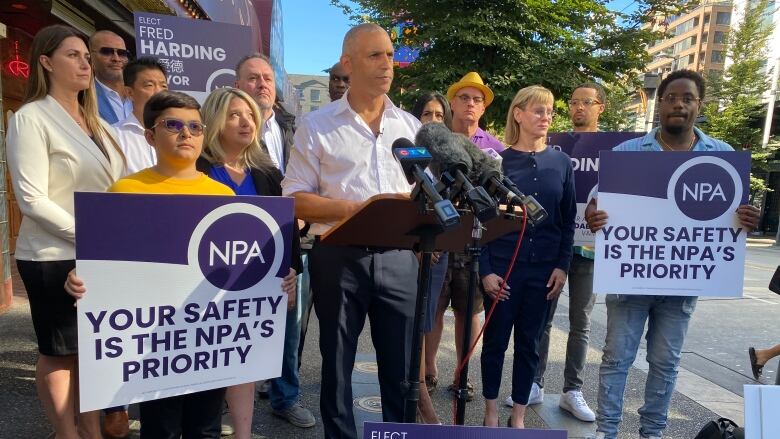 Fred Harding stands at a podium, flanked by supporters and NPA signs.