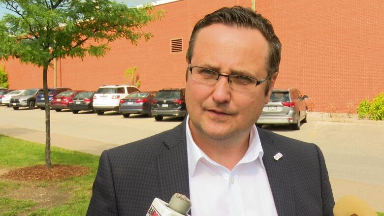 A man wearing a suit answering questions from reporters