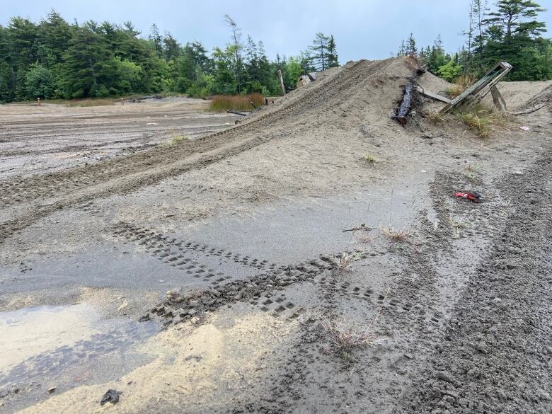 A ramp constructed in sandy-looking mine tailings shows tire tracks where someone has driven over it.