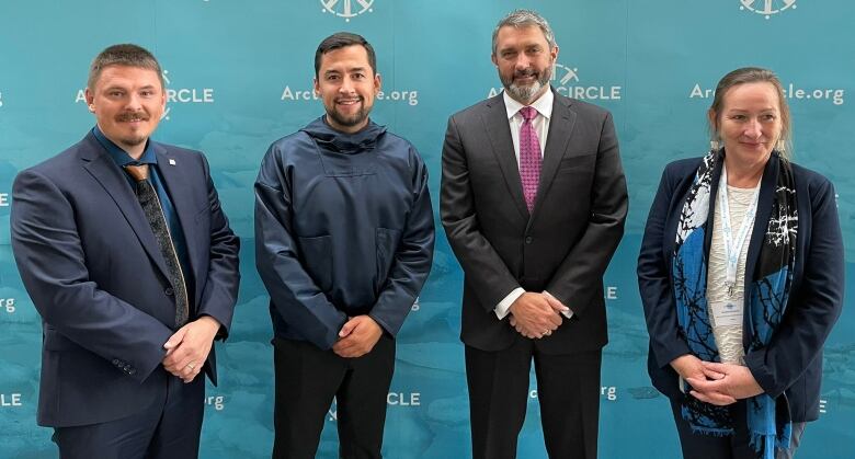 Smiling foursome in suits on Arctic Circle backdrop. 