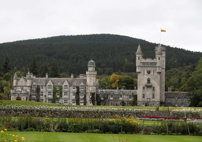 Wide shot of an old stone castle with a green mountain in the background. 