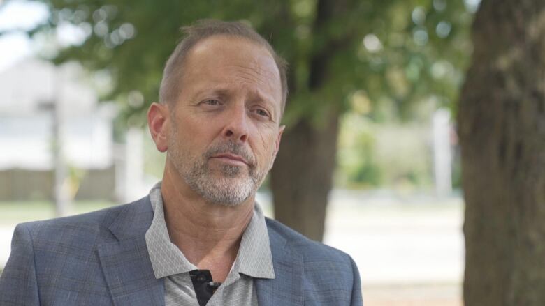 A man in a suit jacket looks off camera.