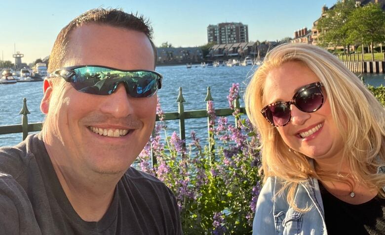 A man and a woman, both wearing sunglasses, smile for the camera. 