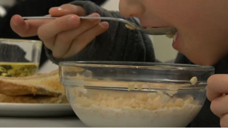 A person eats a spoonful of cereal from a bowl.