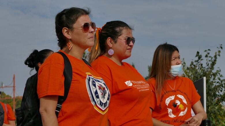 Three women in orange shirts