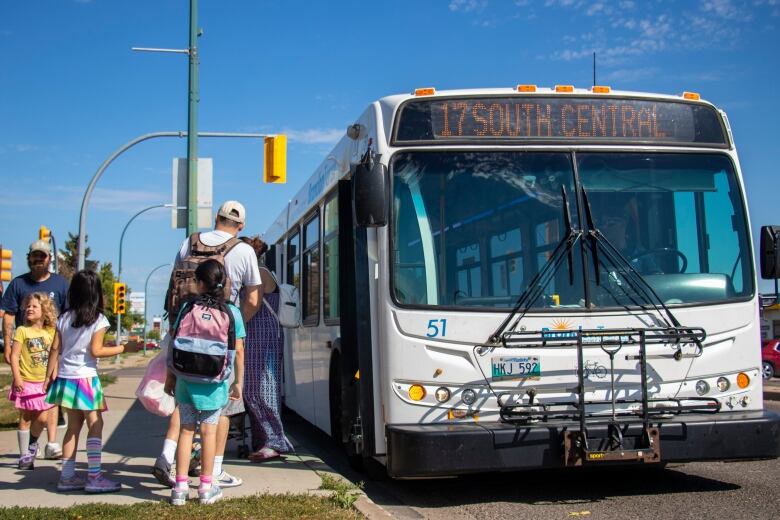 A group of people line up to get on a bus.