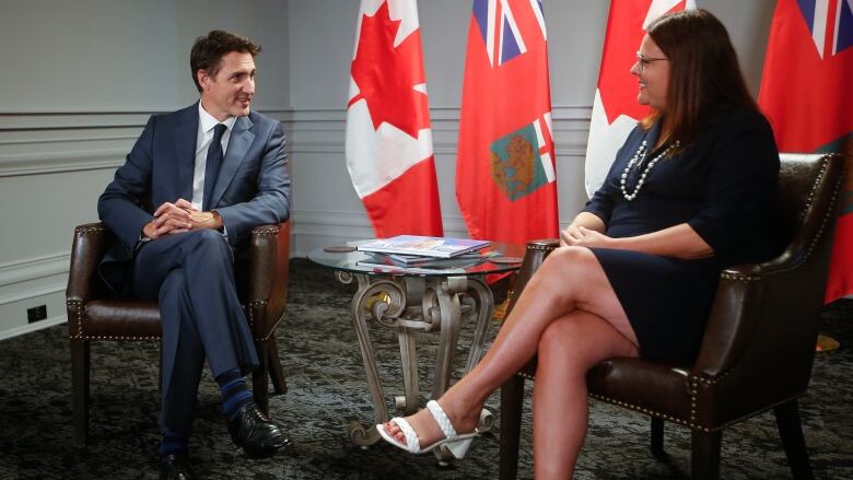 A man and a woman are seated beside each other in separate chairs.