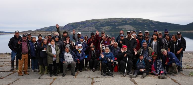 A large group of Innu elders stand as a group, posing for a photo on a wharf.