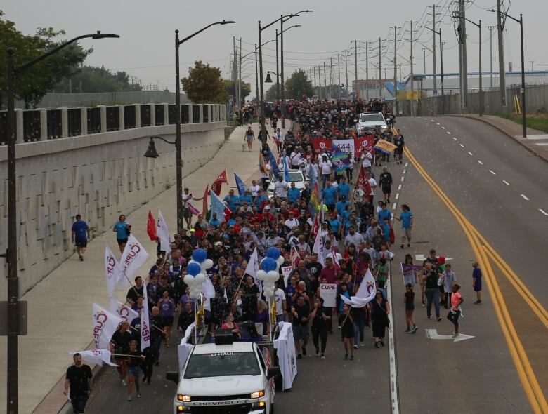 Union workers march in a parade down a road