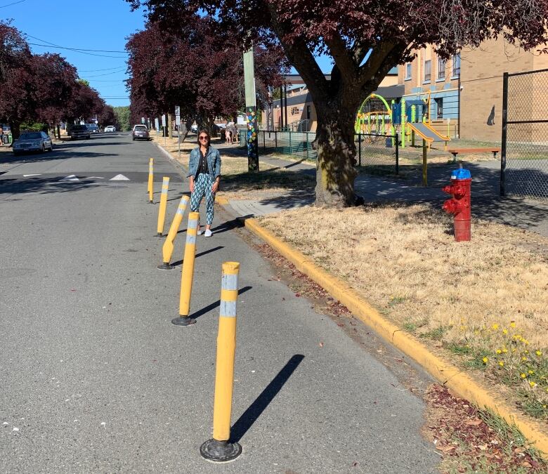 A woman stands near yellow bollards.