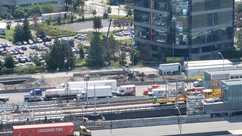 A shot from above of traffic, a light-rail line and some yellow vehicles on it.