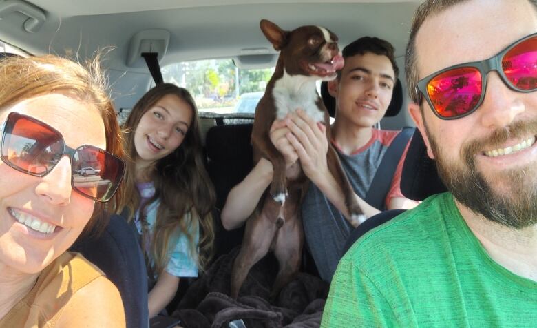 The Nissen family smiles with their dog in a car.