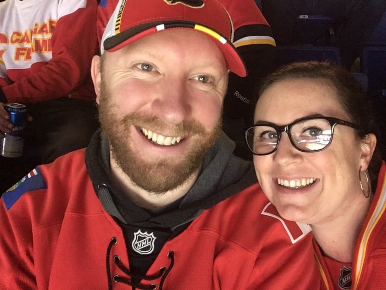 A selfie of a smiling man and woman wearing matching red NHL jerseys.