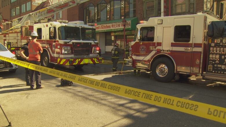 Crime tape is seen in front of a number of fire trucks and firefighters.