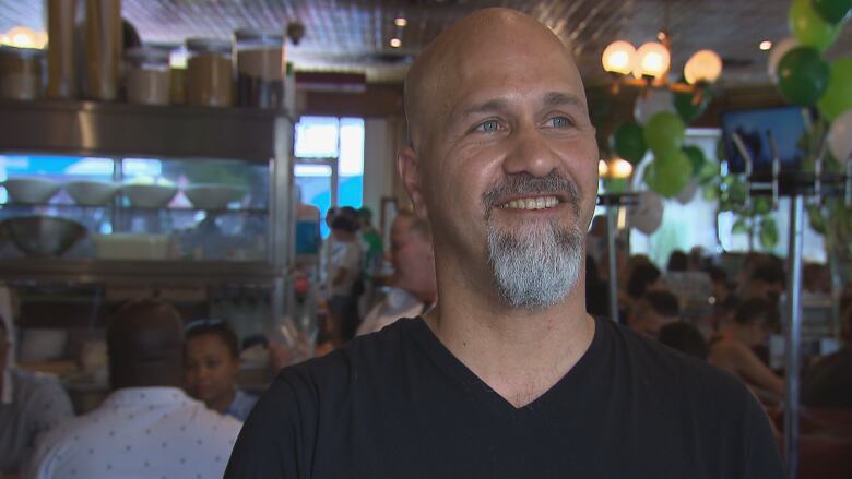 A man smiles in a crowded restaurant. 