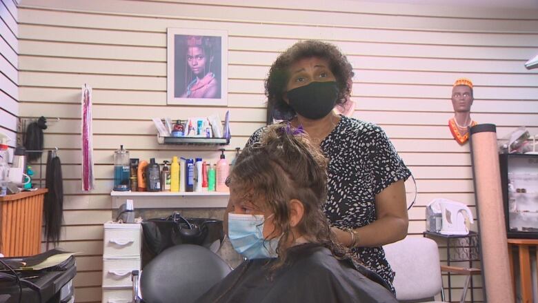 A Black woman doing hair in a salon