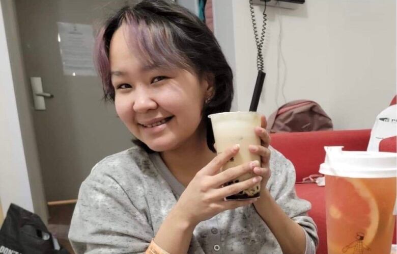 Woman holds bubble tea drink up, smiling. 