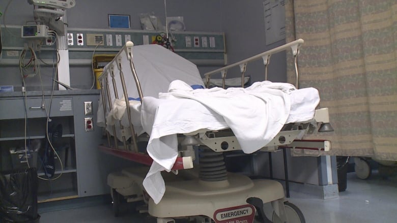 A hospital bed with a white sheet and monitors around it. 