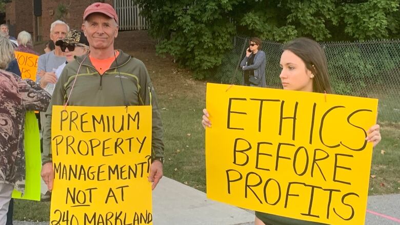 Protesters hold signs reading, 