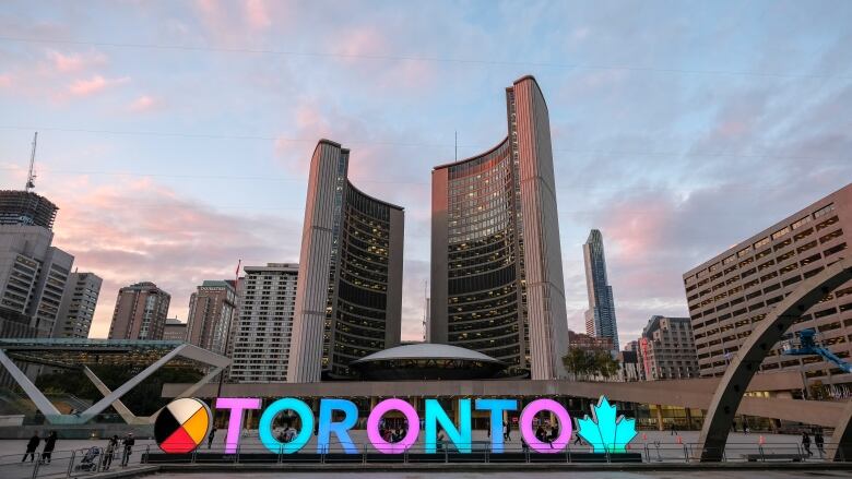 A sign says Toronto in front of the city hall building.