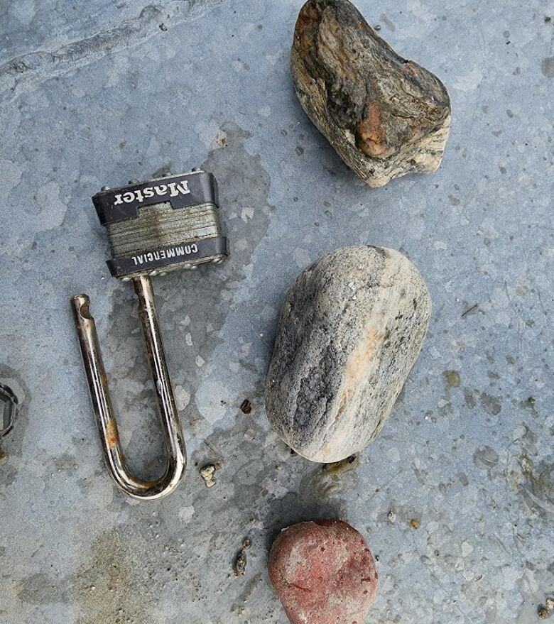 Three rocks next to an open padlock.