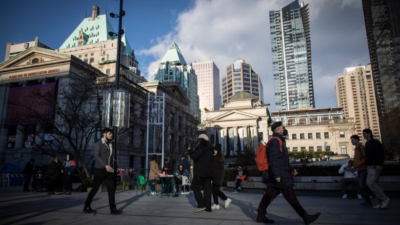 Dozens of people walk past the Vancouver Art Gallery.