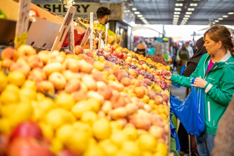 Stacks of fruit and vegetables at an open-air market, as people shop around.