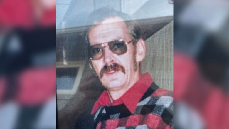 Photo of a man with glasses and facial hair wearing a checkered shirt.