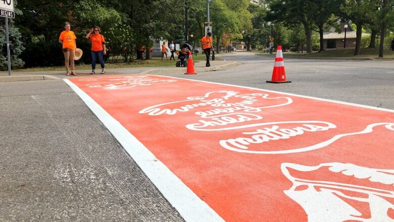 And orange crosswalk painted with the message, 