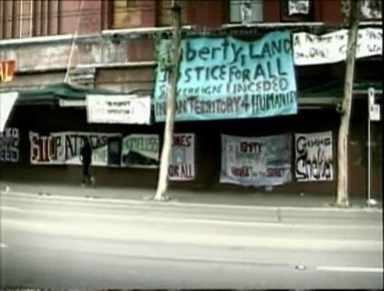 Banners hang from a brick building that read 'liberty, land, justice for all', among other things.