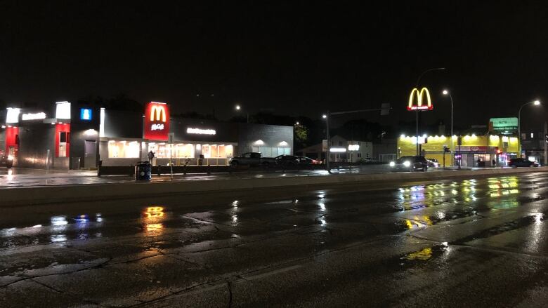 Exterior of McDonald's restaurant at night, with rain-soaked streets in the foreground.