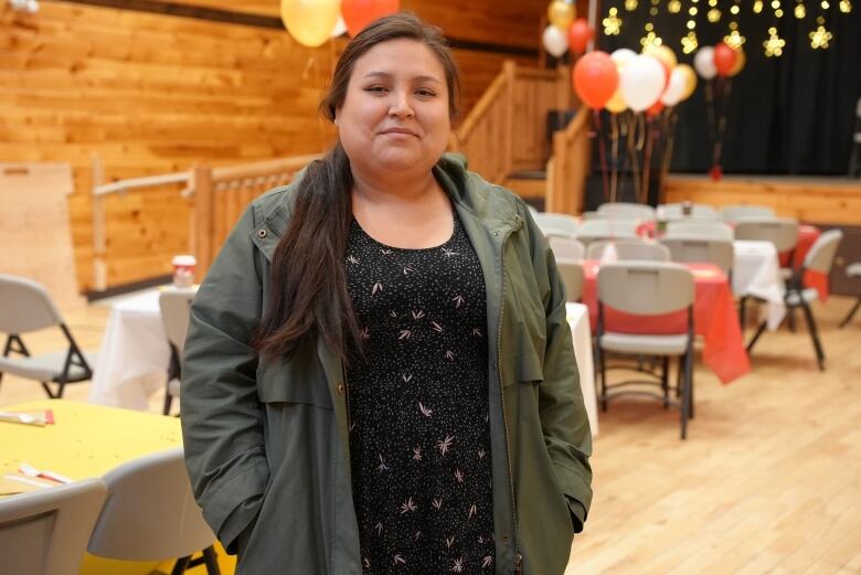 A woman stands against a backdrop of a stage decorated with stars and balloons.