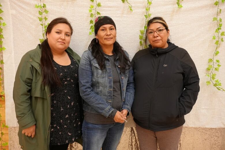 Three women pose against a white backdrop.