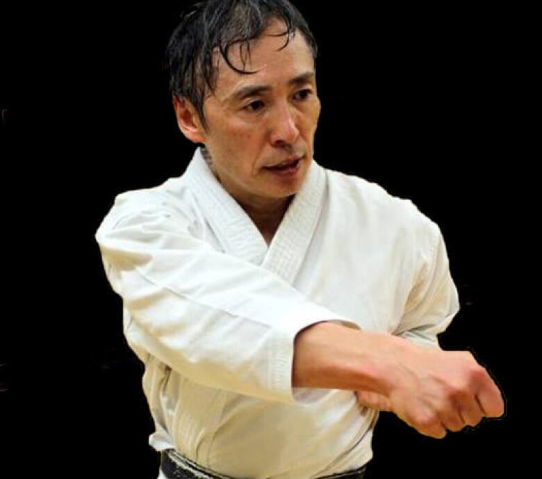 A sweating Japanese man in a karate uniform in a fight pose.