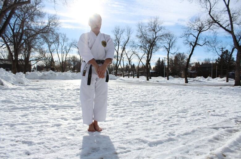 Barefoot man in his karate uniform stands in the snow in an Edmonton park.