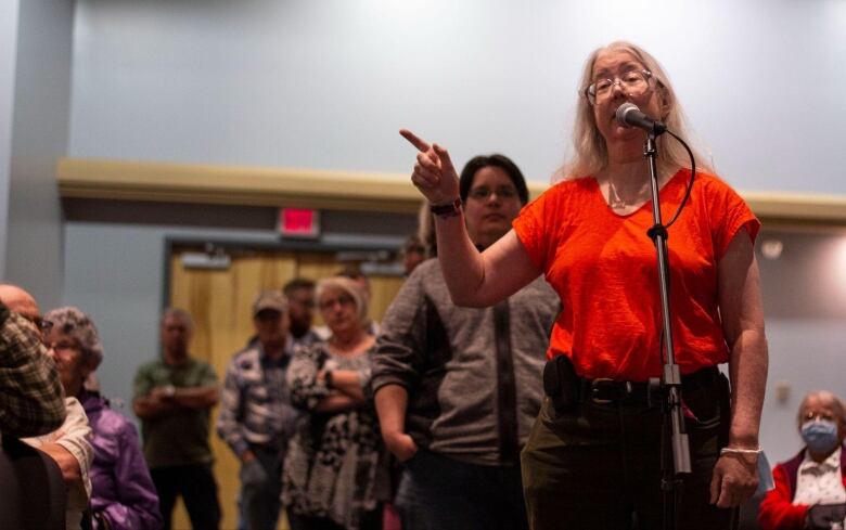 A woman stands at a mic, pointing her finger