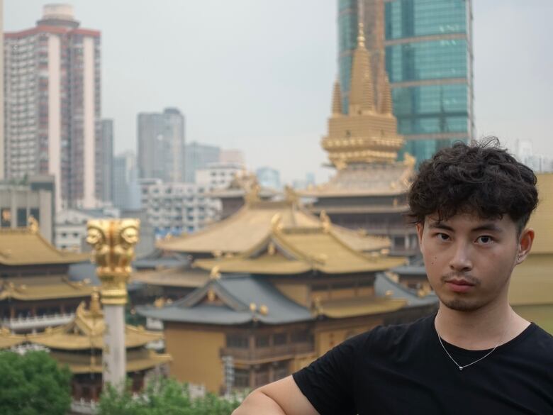 A man poses in front of a cityscape.