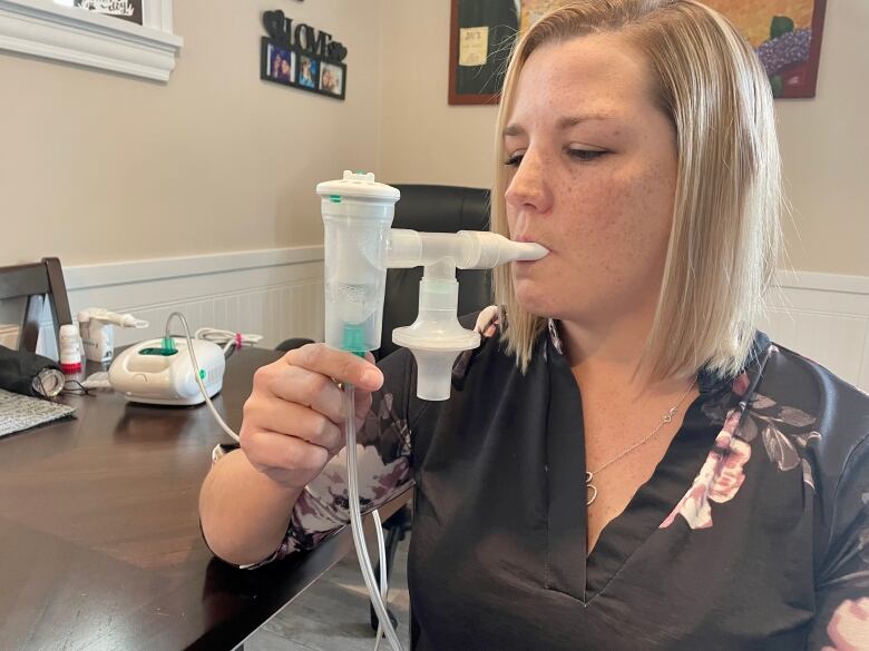 Woman holds an inhaler-type device.