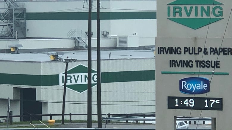 A photo of a grewt buildinbg with dark green strikes and the Irving logo on it.There is a lso a sign with a digital clock and current temperative dispayed.