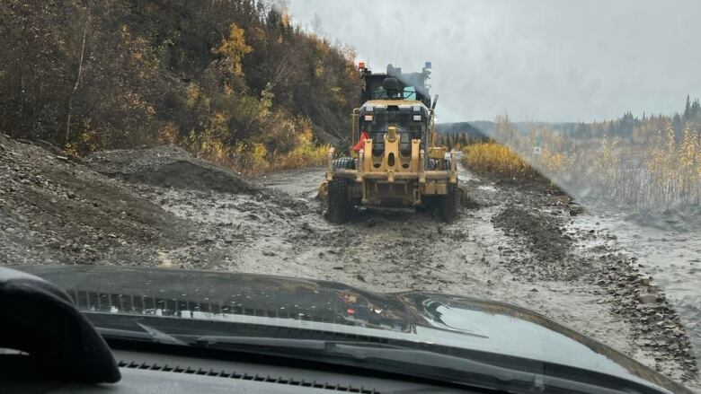 Loader making a gravel road for vehicles to drive on over a washed out road.