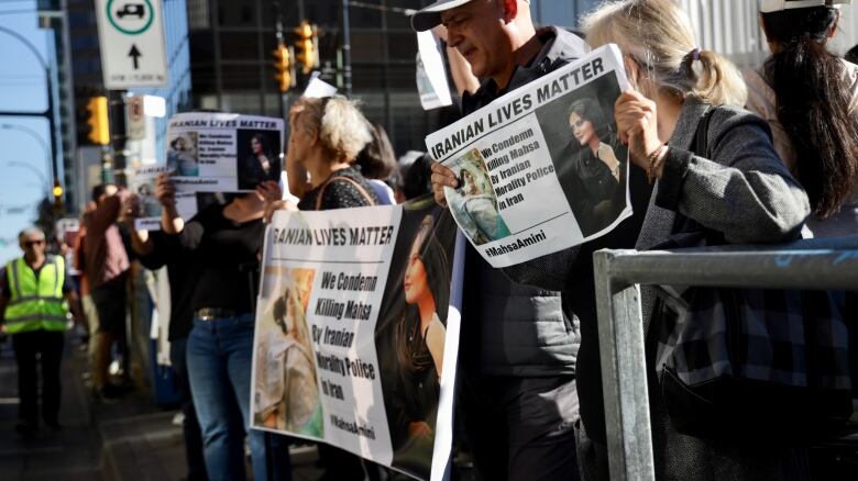 Demonstrators hold up protest signs in downtown Vancouver.