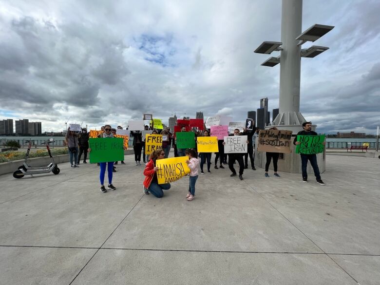 Protesters holding signs on Windsor waterfront protesting. The signs read things like 