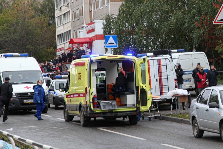 An emergency vehicle is shown on a street with a crowd of people in the background.