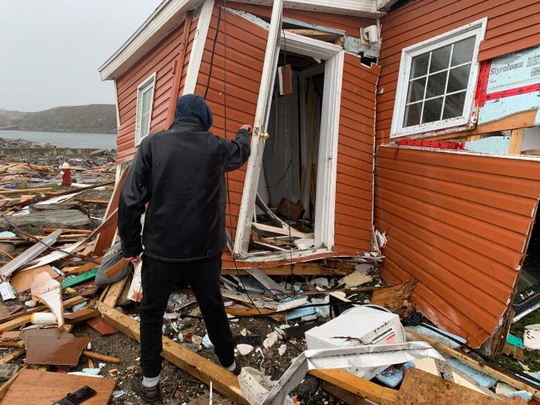 A man in front of wrecked orange home