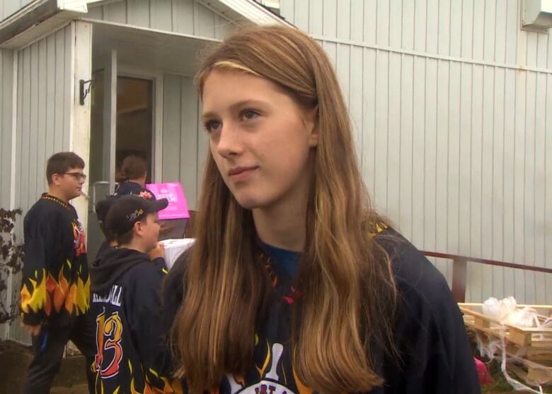 A chest up shot of a young person with long hair wearing a hockey jersey.