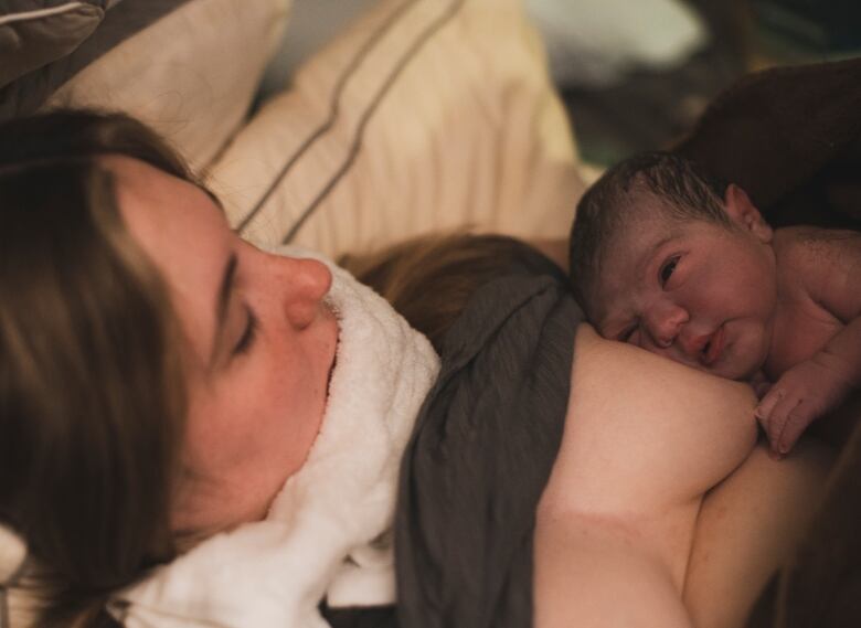 A woman holds a newborn baby to her chest. 