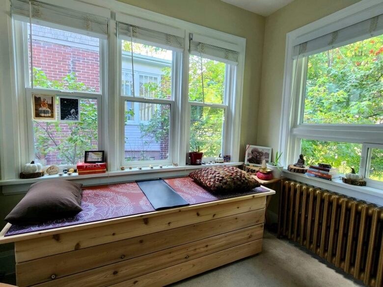 A cedar bench is seen in a sunroom surrounded by trees.