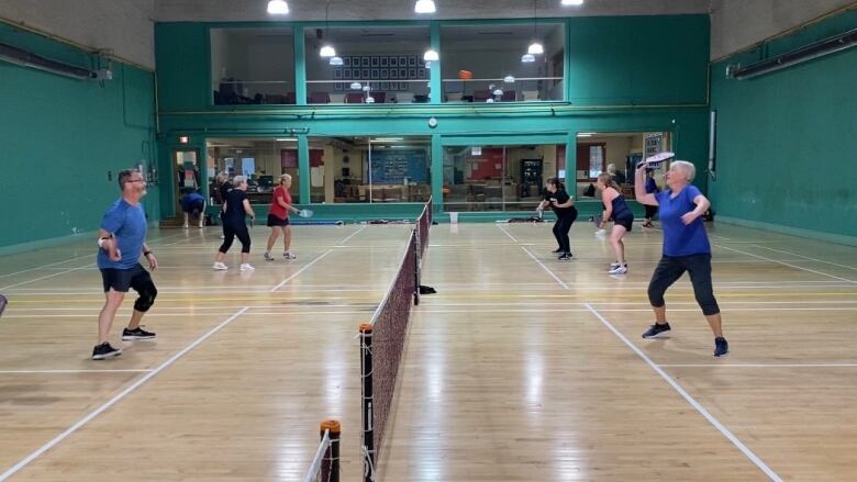 People play pickleball on an indoor court.