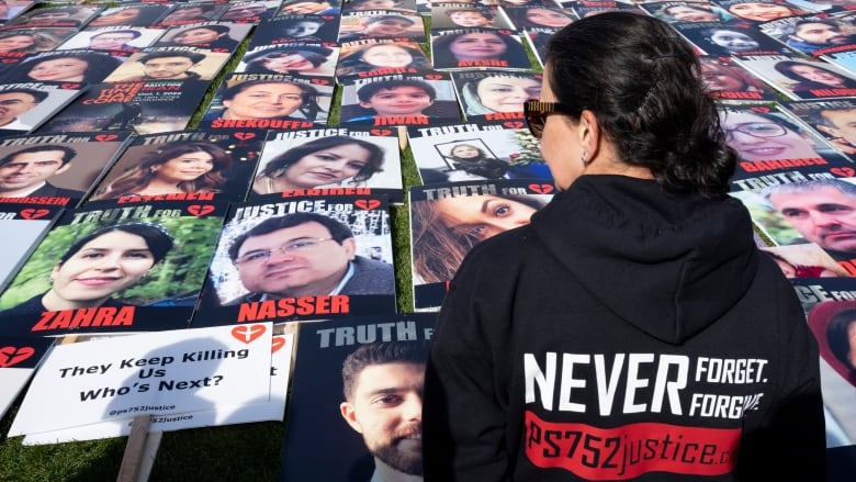 A woman looks at large photos laid on a lawn.