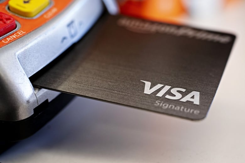 A Visa credit card sticking out of an Interac machine. 